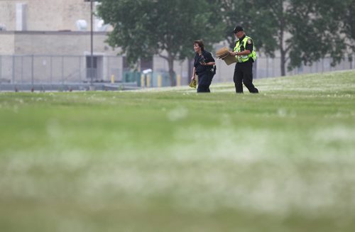 Officers carry bags of suspicious items or evidence in paper bags after being photographed in the field adjacent to Kimberly Hill  near Valley Gardens CC Tuesday where police and cadet units have been searching for the missing women, Thelma Krull.  July 14,, 2015 Ruth Bonneville / Winnipeg Free Press