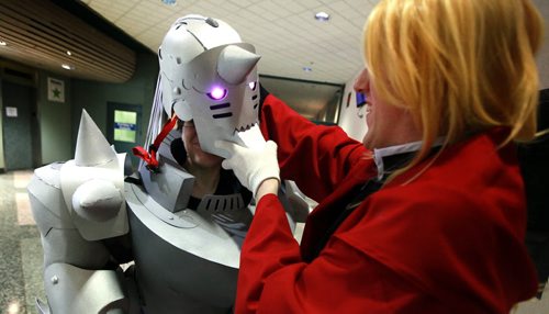 Dakota Noel (left) adjusts Riel Foidart's helmet as they pair adjust costumes beofre joining the lineup of Anime Fans quing up at the Convention Center Friday for Ai-Kon. Riel is in the guise of Alphonse Elric from the program Full Metal Alchemist, Dakota is Edward Elric from the same show. See release below. July 17, 2015 - (Phil Hossack / Winnipeg Free Press)  Ai-Kon, Manitoba's largest Japanese animation (anime) and Asian culture, convention will be held on July 17-19th at the RBC Convention Centre; the event runs around the clock from 12:00 pm on Friday, July 17, 2015 through to 4:00 pm on Sunday, July 19th, 2015. This year marks Ai-Kon's 14th year, bringing over a decade of their anime conventions to the city of Winnipeg. What started out as an event with only 500 in attendance, has grown to over 3000 people who attend annually. Those in attendance take part in the weekend's various festivities such as costume contests, video games, anime showings and various panels relating  to anime and Japanese culture. Attendees also get a chance to meet special guests working in the industry and ask them questions about their experiences. This year Ai-Kon will be welcoming the following guests: Eric Vale (Voice Actor), The 404s (Canadian Geek Improv Team), Greg Ayres (Voice Actor and DJ), Vickybunnyangel Cosplayer (Professional Canadian Cosplayer), Terri Hawkes (Voice Actress) and Ian Sinclair  (Voice Actor). Specific roles and guest information can be viewed at  http://www.ai-kon.org/guests. Ai-Kon (http://www.ai-kon.org) is Manitoba's largest anime convention. An all-ages event, the goal of Ai-Kon is the promotion of Japanese/Asian animation and culture to the public. Started in 2001 by a local anime club, Ai-Kon took a reorganizing hiatus in 2002. It returned in 2003 to become an autonomous event, run by an independent volunteer committee. "Ai" means "love" in Japanese, hence Ai-Kon's slogan "For the Love of Anime".