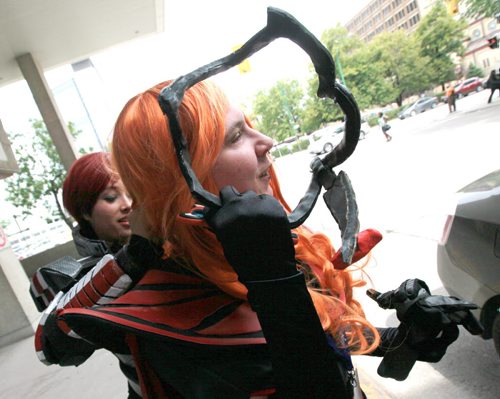 Ashley Davis (left) as Golander Sheppard from Mass Effect adjusts Jaymes Prouten-Christianson's costume. He's portraying Sauron from Lord of the RIngs . The pair was en-route to the RBC Convention Center for the annual Anime Convention.  See release below. July 17, 2015 - (Phil Hossack / Winnipeg Free Press)  Ai-Kon, Manitoba's largest Japanese animation (anime) and Asian culture, convention will be held on July 17-19th at the RBC Convention Centre; the event runs around the clock from 12:00 pm on Friday, July 17, 2015 through to 4:00 pm on Sunday, July 19th, 2015. This year marks Ai-Kon's 14th year, bringing over a decade of their anime conventions to the city of Winnipeg. What started out as an event with only 500 in attendance, has grown to over 3000 people who attend annually. Those in attendance take part in the weekend's various festivities such as costume contests, video games, anime showings and various panels relating  to anime and Japanese culture. Attendees also get a chance to meet special guests working in the industry and ask them questions about their experiences. This year Ai-Kon will be welcoming the following guests: Eric Vale (Voice Actor), The 404s (Canadian Geek Improv Team), Greg Ayres (Voice Actor and DJ), Vickybunnyangel Cosplayer (Professional Canadian Cosplayer), Terri Hawkes (Voice Actress) and Ian Sinclair  (Voice Actor). Specific roles and guest information can be viewed at  http://www.ai-kon.org/guests. Ai-Kon (http://www.ai-kon.org) is Manitoba's largest anime convention. An all-ages event, the goal of Ai-Kon is the promotion of Japanese/Asian animation and culture to the public. Started in 2001 by a local anime club, Ai-Kon took a reorganizing hiatus in 2002. It returned in 2003 to become an autonomous event, run by an independent volunteer committee. "Ai" means "love" in Japanese, hence Ai-Kon's slogan "For the Love of Anime".