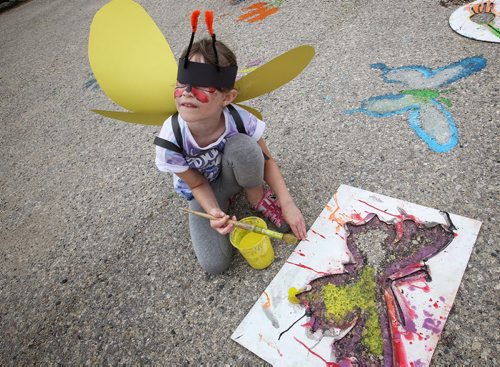 Ava Colbourn, 7, looks up while painting a butterfly in the parking lot of the Living Prairie Museum during 9th Annual Monarch Butterfly Festival. 150719 July 19, 2015 MIKE DEAL / WINNIPEG FREE PRESS