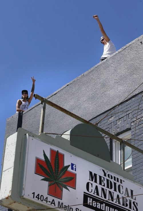 Supporters of Glenn Price wave to passing motorists on Main street as Price began selling medical marijuana again Tuesday morning at his shop Your Medical Cannabis Headquarters, despite a police order last Tuesday to stop.  Aidan Geary story Wayne Glowacki / Winnipeg Free Press July 21 2015