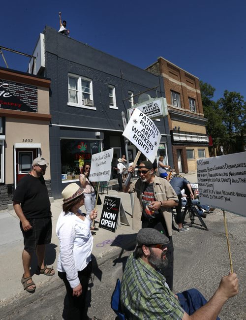 Supporters of Glenn Price waved to passing motorists on Main street as Price began selling medical marijuana again Tuesday morning at his shop Your Medical Cannabis Headquarters, despite a police order last Tuesday to stop.  Aidan Geary story Wayne Glowacki / Winnipeg Free Press July 21 2015