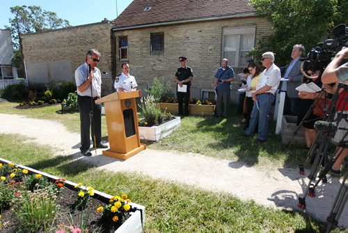 City councillor Ross Eadie, Mynarski ward, talks to the media about the  Winnipeg Police Service's 2014 Annual Report at Selkirk Community Garden Wednesday morning.  Superintendent Danny Smyth (in white uniform),       July 22,, 2015 Ruth Bonneville / Winnipeg Free Press