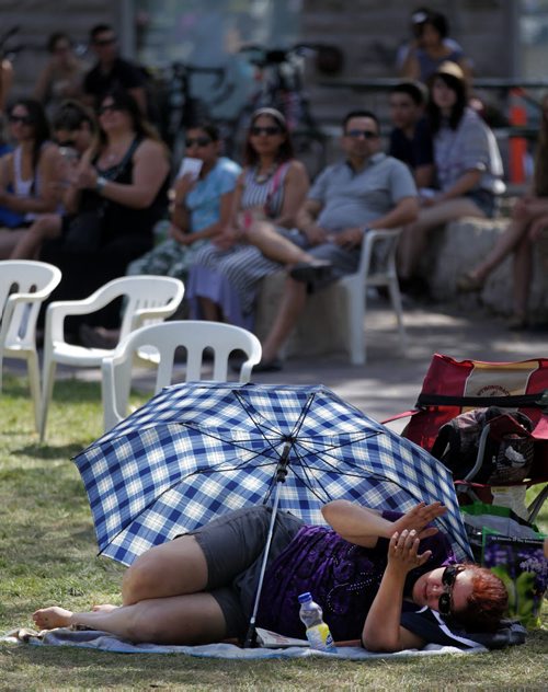 Its all in how you look at it......Under the shelter of her umbrella from the sun's heat, Sonia Cashman gets her own perspective on a performance at the Fringe Festival Free Stage Wednesday afternoon.  July 22, 2015 - (Phil Hossack / Winnipeg Free Press)