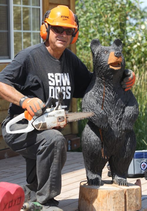 Russ Kubara displays his techniques on how to carve wood with a chainsaw at Tyndall Firewood Supply Ltd near Tyndall, Manitoba  - He teaches workshops in spring and fall- He poses with a bear he carved-See David Sanderson story- July 23, 2015   (JOE BRYKSA / WINNIPEG FREE PRESS)