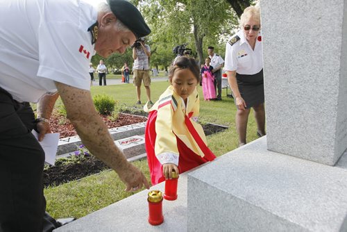 July 26, 2015 - 150726  - Korean war veteran Tony Their assists Hanna Jang, 7, as she places a candle to remember the people who gave their lives in the Korean war during a ceremony in Winnipeg this afternoon,  Monday, July 27, 2015. Members of Unit 17 (Manitoba) of the Korea Veterans Association held a candlelight service at Brookside Cemetery  to honour the 516 who gave their lives during  the Korean War that ended with a ceasefire to hostilities on July 27, 1953.