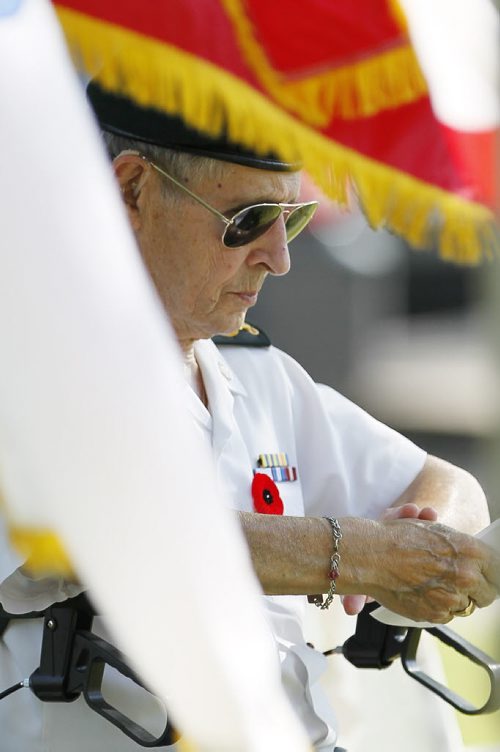 July 26, 2015 - 150726  - Photographed between the Korean and Canadian flags Korean war veteran Hugh MacKenzie takes a moment of silence to remember the people who gave their lives in the Korean war during a ceremony in Winnipeg this afternoon,  Monday, July 27, 2015. Members of Unit 17 (Manitoba) of the Korea Veterans Association held a candlelight service at Brookside Cemetery  to honour the 516 who gave their lives during  the Korean War that ended with a ceasefire to hostilities on July 27, 1953. John Woods / Winnipeg Free Press