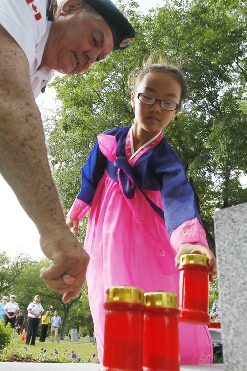 July 26, 2015 - 150726  - Korean war veteran Tony Their assists Jena Jang, 9, as she places a candle to remember the people who gave their lives in the Korean war during a ceremony in Winnipeg this afternoon,  Monday, July 27, 2015. Members of Unit 17 (Manitoba) of the Korea Veterans Association held a candlelight service at Brookside Cemetery  to honour the 516 who gave their lives during  the Korean War that ended with a ceasefire to hostilities on July 27, 1953.