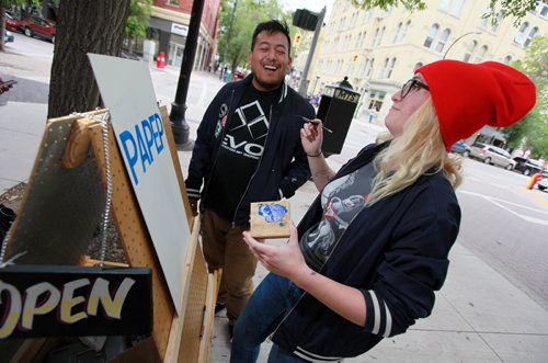 Cycling Sign Painters Bridgette Ellen and Joseph Pilapil share a laugh Tuesday working on a sign for the story. See  Dave Sanderson story. July 27, 2015 - (Phil Hossack / Winnipeg Free Press)