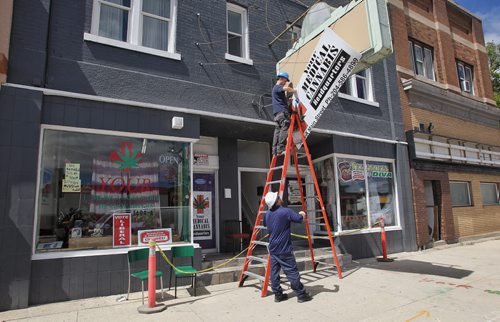 A city contractor removes the sign at the store that was illegally selling marijuana until the couple that runs it was arrested Tuesday afternoon.  150804 August 04, 2015 MIKE DEAL / WINNIPEG FREE PRESS