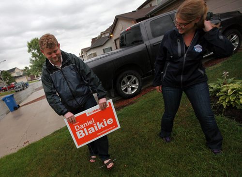 Daniel Blaikie poses pushing a campaign sign into a transcona Lawn Wednesday evening assisted by Breigh Kusmack. The sign at 171 Chadwick Cr. was the first in the area.  See Mary Agnes story. August 5, 2015 - (Phil Hossack / Winnipeg Free Press)