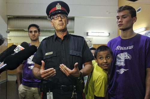 Drop Zone participant, Junior Whitford, 8, steps in during a media scrum by Staff Sargent Ron Johansson. Johansson and Police Chief Devon Clunis decided to hold the daily media briefing at the Turtle Island Neighbourhood Centre so that they could highlight the good work that programs like Drop Zone, a summer youth sports drop-in, are vital to help children gain confidence and learn "leadership, integrity and good citizenship." 150806 August 06, 2015 MIKE DEAL / WINNIPEG FREE PRESS