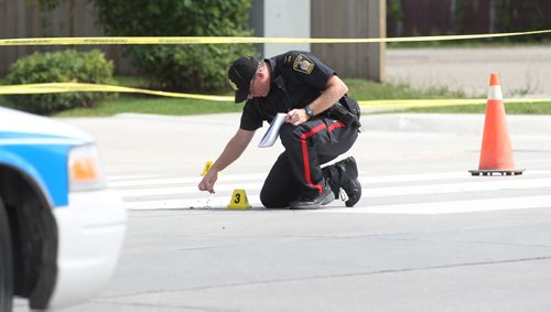 Police Officers investigate a pedestrian  accident involving an older woman crossing at a cross walk on St. Annes Rd. at Compark Saturday afternoon.   An Officer looks at a pair of glasses belonging to the pedestrian  near the crosswalk.  Aug 8, 2015 Ruth Bonneville / Winnipeg Free Press