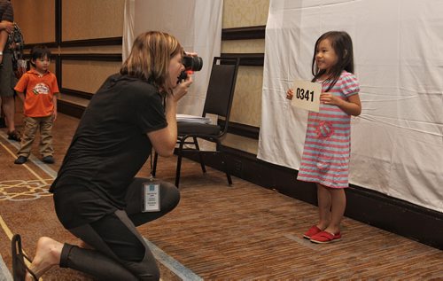 Alexa Chan, 5, holds a numbered sign while getting her photo taken during the casting process. Way over 2,000 hopeful extras stood in line during a casting call at Fairmont Sunday for a movie starring Dennis Quaid, Peggy Lipton and Britt Robertson. 150809 August 09, 2015 MIKE DEAL / WINNIPEG FREE PRESS