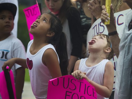 Tianna Severight (left) and Jenna Head catch rain droplets with their tongues at a protest bring attention to problems with flood channels at the Manitoba Legislative Building in Winnipeg on Wednesday, Aug. 12, 2015.   Mikaela MacKenzie / Winnipeg Free Press