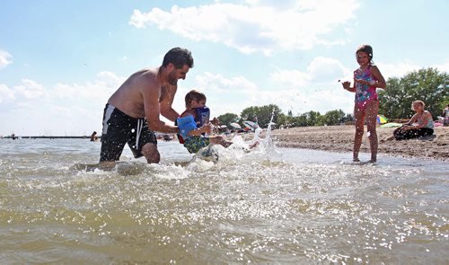 Three-year-old Ryan Enns gets spun around in the water by his dad, Mike, while his older sister Janelle, 9yrs look on while at Gimli beach with family Thursday.  Standup hot weather photo.   Aug 13, 2015 Ruth Bonneville / Winnipeg Free Press