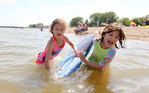 Ten-year-old Nayeli Toews and her sister Amaris - 7yrs scream as Nayeli attempts to stand on a foam surfboard while hanging onto her sister, Amaris while spending the day at Gimli beach with family Thursday.  Standup hot weather photo.   Aug 13, 2015 Ruth Bonneville / Winnipeg Free Press