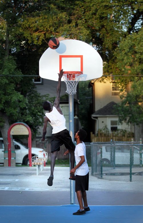 Didi Deng goes up for the shot while Isayas Tekeste watches while playing a little one on one basketball at Magnus Eliasson Community Center's outdoor court Thursday evening. See Melessa Matin's story. August 13, 2015 - (Phil Hossack / Winnipeg Free Press)