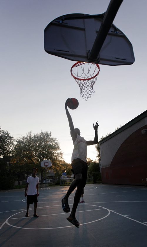 Didi Deng goes up for the shot while Isayas Tekeste watches while playing a little one on one basketball at Magnus Eliasson Community Center's outdoor court Thursday evening. See Melessa Matin's story. August 13, 2015 - (Phil Hossack / Winnipeg Free Press)