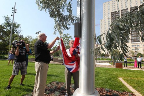 Jerry Gray (black shirt) and Garry Hilderman both with Friends of Upper Fort Garry, cut the ribbon and raise flags at the official unveiling of Upper Fort Garry  at the new provincial park on Main street Friday.   Aug 14, 2015 Ruth Bonneville / Winnipeg Free Press
