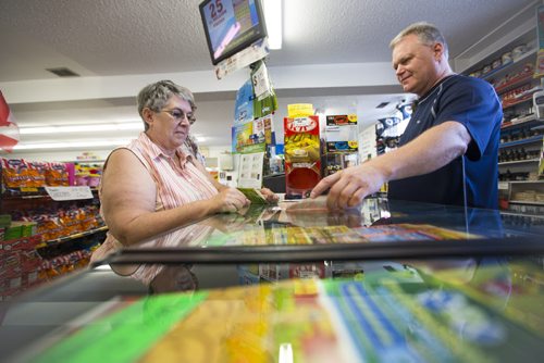 Donna Templeton buys lottery tickets from Ken Taylor, manager of Video 1001, on Mountain Avenue on Friday, Aug. 14, 2015.  The store also has ice cream, slushies, food, lotto tickets, laundry, and more. Mikaela MacKenzie / Winnipeg Free Press