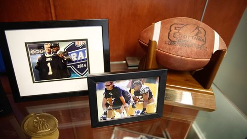 Photos on the shelf of Riley's office from his time coaching in the NFL and the game ball from the 1988 Grey Cup game when the Bombers beat the B.C. Lions in Ottawa. August 20, 2015 - Melissa Tait / Winnipeg Free Press