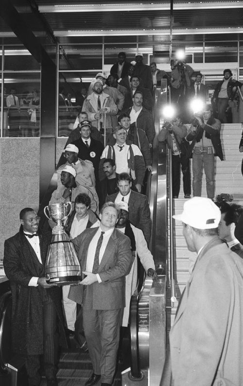 The Winnipeg Blue Bomber players wave at crowds of cheering fans as they make their way down the escalator at Winnipeg's airport with the Grey Cup in their hands after beating the BC Lions in Ottawa.   Wayne Glowacki, Nov 28 1988