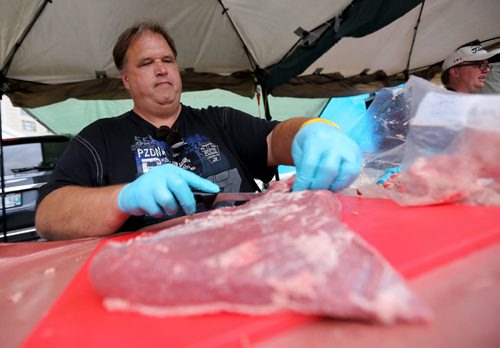 Gary Rose from Smokin' Squealers BBQ trims the fat off a beef brisket, that will then take around 10 hours to cook, at the Winnipeg BBQ and Blues festival, Friday, August 21, 2015. (TREVOR HAGAN/WINNIPEG FREE PRESS)