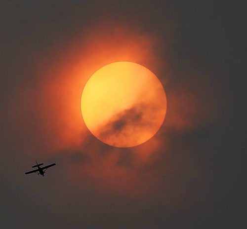 A small plane flies in front of the sun which is partially blocked by clouds, Friday, August 21, 2015. (TREVOR HAGAN/WINNIPEG FREE PRESS)