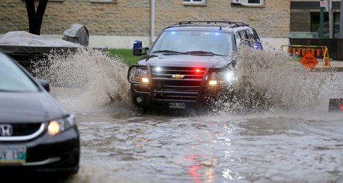 A police vehicle turns onto River Avenue near Harkness Avenue into a deep puddle, Saturday, August 22, 2015. (TREVOR HAGAN/WINNIPEG FREE PRESS)
