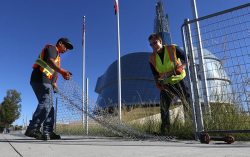 At left, Craig Chief and Desmond Proulx with Midwest Fencing pack up the fencing Tuesday morning that has surrounded the Canadian Museum for Human Rights for the past two years protecting the native grasses as they took hold.  Wayne Glowacki / Winnipeg Free Press August 25   2015