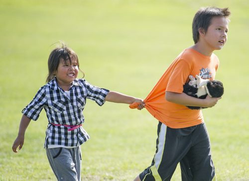 DAVID LIPNOWSKI / WINNIPEG FREE PRESS 150828 August 28, 2015  Anastasia Berens (age 5, left) chases her friend Leland McKay (age 9) who is holding a puppy during an event that included an announcement for the future site of a bridge over Pigeon River at Berens River Friday August 28, 2015 in Berens River. The bridge is part of the next stage of construction of the east-side road by The Manitoba East Side Road Authority. This stage would link Berens River to Bloodvein to the south. A Treaty Days event was to take place after the announcement. EDITOR'S NOTE: The image can be used as a standup.