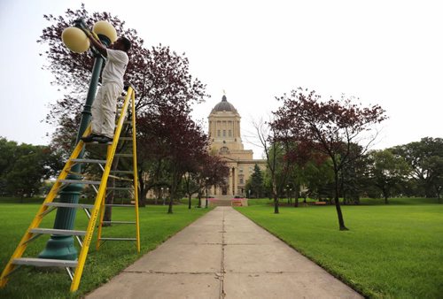 Okbmichael Habtzgighi prepares a lamp to be painted at the Manitoba Legislative Building, Saturday, August 29, 2015. (TREVOR HAGAN / WINNIPEG FREE PRESS)