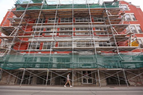 A pedestrian walks through scaffolding at an apartment building on Osborne Street at Roslyn Road, Saturday, August 29, 2015. (TREVOR HAGAN / WINNIPEG FREE PRESS)