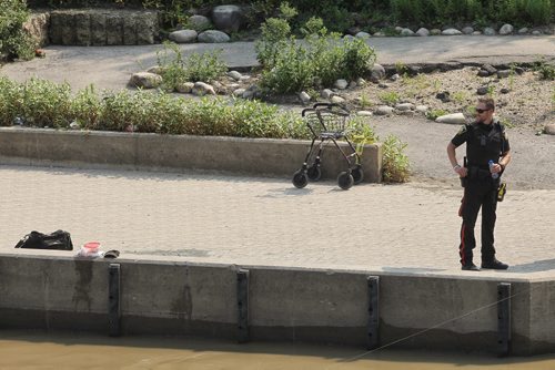 Winnipeg Police keep watch over the scene where a reportedly elderly male who was fishing on a dock fell into the Red River close to the east side of the Norwood Bridge. Unconfirmed reports are he fell in with his walker.  150830 August 30, 2015 MIKE DEAL / WINNIPEG FREE PRESS