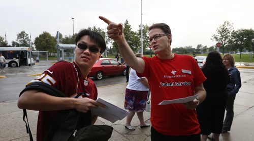 Student Manson Junji Chen gets directions to class from new president & CEO of Red River College, Paul Vogt Monday morning on  the first day of classes at Red River College. Paul along with members of Red River College's Executive and Alumni Team were out welcoming students back at the main entrance of the Notre Dame Campus. Wayne Glowacki / Winnipeg Free Press August 31  2015