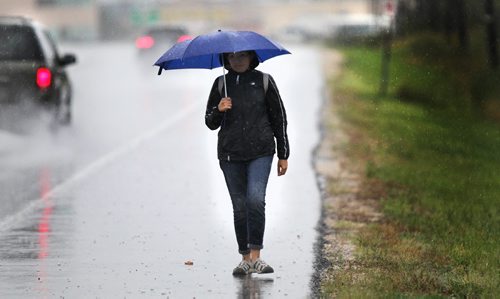 A soggy pedestrian trudges along McGillvary ave Friday afternoon after a downpour flooded streets and overpasses. A string of thunderstorms is lined up to blast the Red River Valley this afternoon and evening. September 4, 2015 - (Phil Hossack / Winnipeg Free Press)