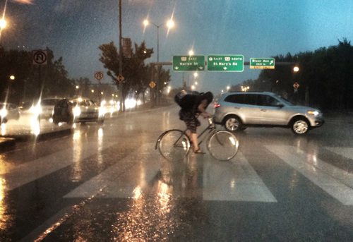 A cyclist races through the storm that hit Winnipeg Friday afternoon. Photo taken on Main Street near Broadway. BORIS MINKEVICH / WINNIPEG FREE PRESS PHOTO Sept. 4, 2015