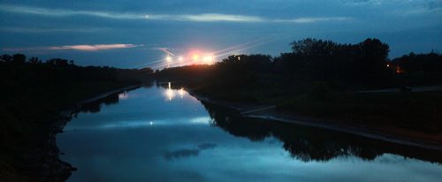 With lights from US and Canadian Border stations reflected the red river flows arcorss the international boundary near Emerson. September 16, 2015 - (Phil Hossack / Winnipeg Free Press)  See Carol Sanders story, BUSY SUMMER ON MANITOBAS UNDERGROUND RAILROAD  -- While thousands seeking asylum in Europe amass on its borders, a growing surge of refugee claimants quietly slip into Canada under the cover of darkness at a Manitoba border town. Most local residents dont see them because they arrive under the cover of darkness while people are sleeping, said Wayne Arseny, Emersons former mayor. They dont want be to be spotted. CBSA says nearly twice as many asylum seekers   walked up to the port of entry into Canada by way of Manitoba this summer compared to last  year. Some in the settlement community are calling the influx the underground railroad with many refugee claimants crossing here and moving on to Toronto and B.C.  Why here? Why now? What does it mean for Winnipeg and its already overwhelmed settlement services? 15 SANDERS (ART?)