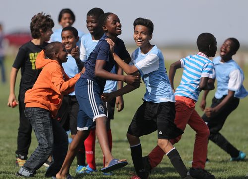 Friends rush the field to join the players from IRCOM, The Immigrant and Refugee Community Organization of Manitoba Inc. soccer team, after defeating St. Johns Ravenscourt during the final game of the boys under 13 city recreation final at John Blumberg, Saturday, September 26, 2015. (TREVOR HAGAN/WINNIPEG FREE PRESS)