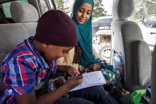 Karin Gordon travels to Emerson, MB to pick up refugees who have made it across the border with the United States. Somali refugee Amin, 6, with his mom Sahra Ali Ahmed, insists on writing his name for the reporter Sunday just before leaving Emerson, MB, for Winnipeg. 150927 - Sunday, September 27, 2015 -  MIKE DEAL / WINNIPEG FREE PRESS