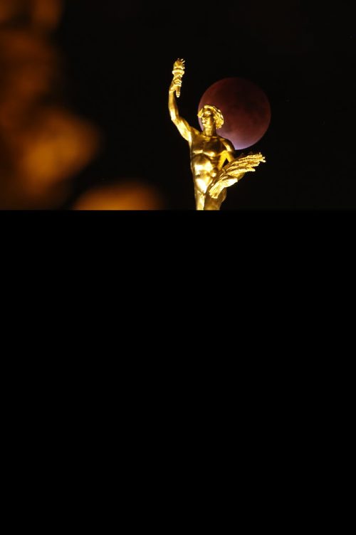 Lunar eclipse on a Supermoon appears behind the Golden Boy at the Manitoba Legislature  in Winnipeg Sunday, September 27, 2015. THE CANADIAN PRESS/John Woods