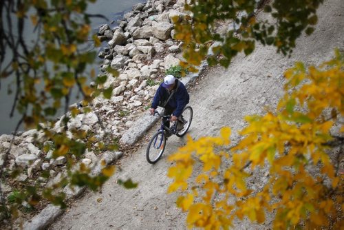 A cyclist is framed by yellowing leaves as he makes his way along the river walk by the Assiniboine River Wednesday morning.  150930 September 30, 2015 MIKE DEAL / WINNIPEG FREE PRESS