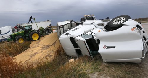 Workers retrieve the grain from an overturned semi-trailer that blocked one of the northbound lanes of Highway 7 just north of the Perimeter Highway at Road 69 Wednesday afternoon. The uninjured driver was out helping with the cleanup.   Wayne Glowacki / Winnipeg Free Press October 7 2015