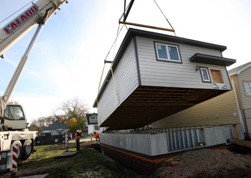 A modular home is set on its foundation by a giant crane on Ferry St Friday  The modular home was built by Riverbend Building Supplies on the Riverbend Colony near Carberry, Manitoba- The pre cast basement was build by Superior Walls- The modern construction technique gives superior basement wall construction that will not crack cracking or have water leakage- From start to finish a project can be completed in 3 weeks vs. 3 months using tradition on site construction- Costs are about 15-20% less than regular on site builders- Standup Photo-Oct 10, 2015   (JOE BRYKSA / WINNIPEG FREE PRESS)