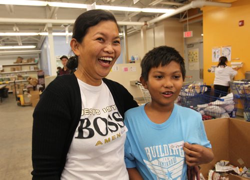 Rita Salazar and her ten-year-old John are all smiles as they help sort food items that are being packaged up for Thanksgiving hampers at Winnipeg Harvest Saturday afternoon.  Her family of four recently  immigrated to Canada in June as landed immigrants and they wanted to give back to the community that has helped them settle into a new country they now call home. See Carol Sanders story. Oct 10, 2015 Ruth Bonneville / Winnipeg Free Press