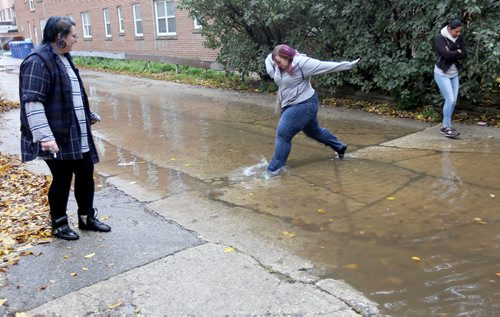 Erika Brown and Jessica Zawadowski nagivate through a large puddle on Assiniboine Avenue, Monday, October 12, 2015. (TREVOR HAGAN/WINNIPEG FREE PRESS) for carol sanders story