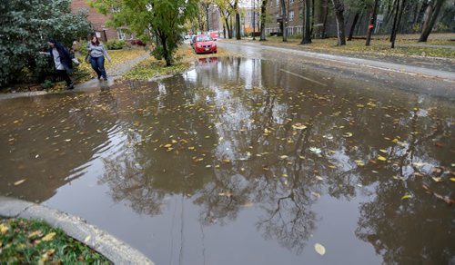 Erika Brown and Jessica Zawadowski nagivate around a large puddle on Assiniboine Avenue, Monday, October 12, 2015. (TREVOR HAGAN/WINNIPEG FREE PRESS) for carol sanders story