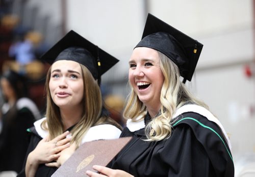 Alanna Marie Hueging (left) and Lindsey Hower are all smiles as they look  to family and friends in the stands after receiving their Bachelor of Nursing degree at the 48th Annual Fall Convocation Wednesday held at Investors Group Athletic Centre at the U of M.  The two day event will continue Thursday at 3;30pm with a much larger group of grads. Standup Photo Oct 21, 2015 Ruth Bonneville / Winnipeg Free Press