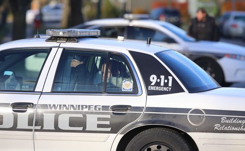 A woman and children sit in the back of a Winnipeg Police cruiser on Keenlyside Street at a standoff, Sunday, October 25, 2015. (TREVOR HAGAN / WINNIPEG FREE PRESS)